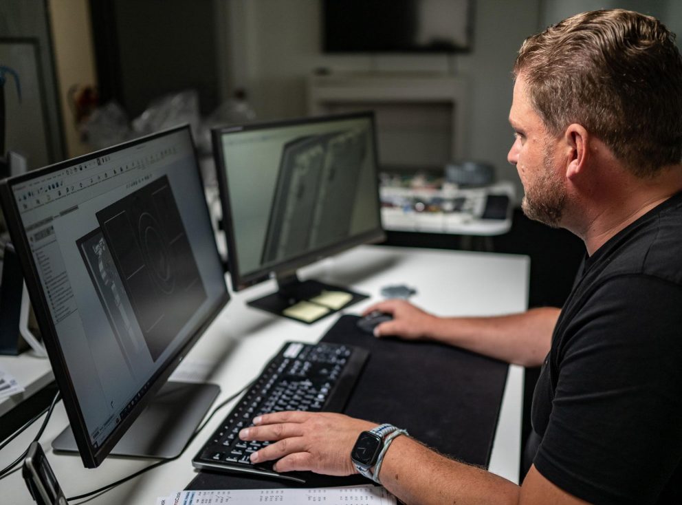 Ein Ingenieur arbeitet vor zwei Monitoren an einem Computer