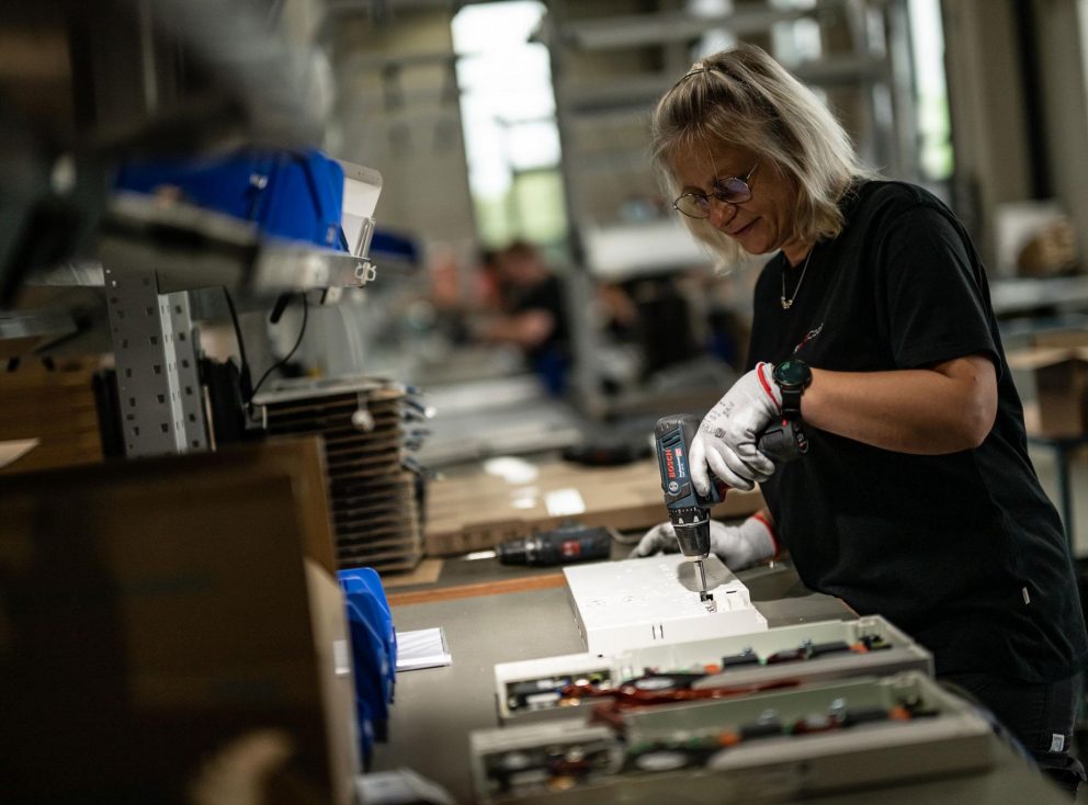 Eine Frau arbeitet in einer Fabrik mit einer Maschine.